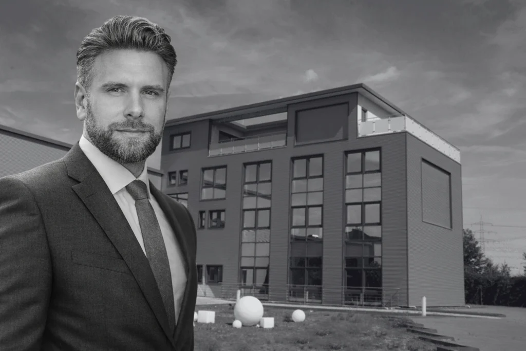 Robin Henn - stehend im Anzug vor unserem Firmengebäude in Wesseling